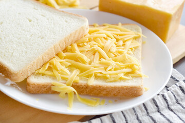 Grated cheese on bread.  Cheese sandwich preparation. 