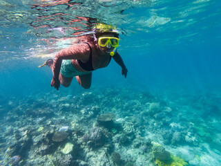 Indian woman snorkeling over reef in the blue tropical waters of Fiji