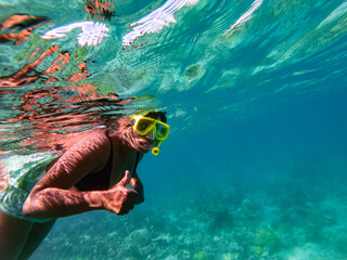 Indian woman snorkeling and giving thumbs under water in the blue tropical waters of Fiji