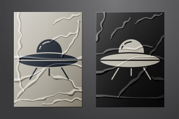 White UFO flying spaceship icon isolated on crumpled paper background. Flying saucer. Alien space ship. Futuristic unknown flying object. Paper art style. Vector