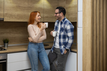 Young man and woman standing in kitchen and talking