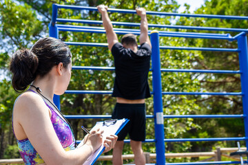 portrait of female personal trainer taking note and keeping track of exercises and repetitions of...