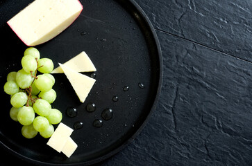 Top View of Cheese and Green Seedless Grapes on Black Table