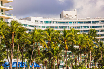 View of building behind palm trees on cloudy sky background. Miami Beach. USA.