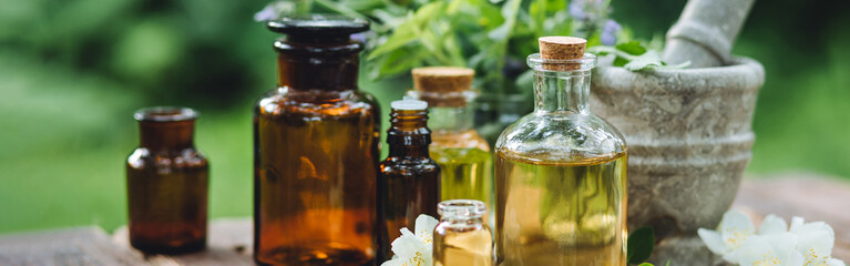 Herbal pure natural cosmetic ingredients on wooden background. Mix of holistic flowers and herbs, salt, massage herb-infused essential oil in glass bottles. Aromatherapy, fragrance production. Banner