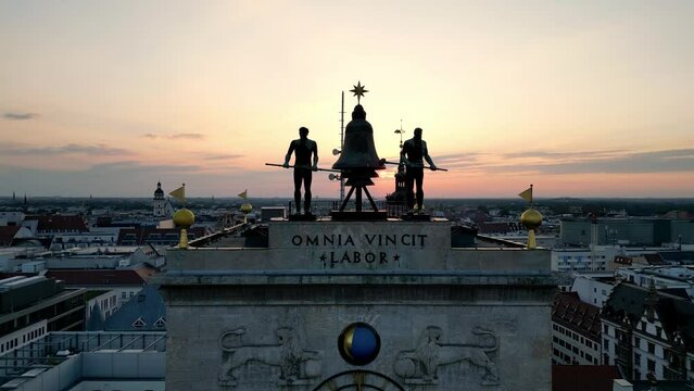 Krochhochhaus. Leipzig, Germany. At the building's peak, there's a bell tower with male figures striking clocks and a Latin inscription 'OMNIA VINCIT LABOR.' Below, there are moon phases.