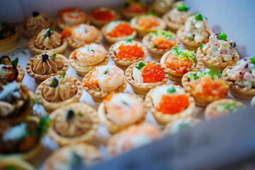 A box of tartlets stuffed with salads and seafood. Catering.