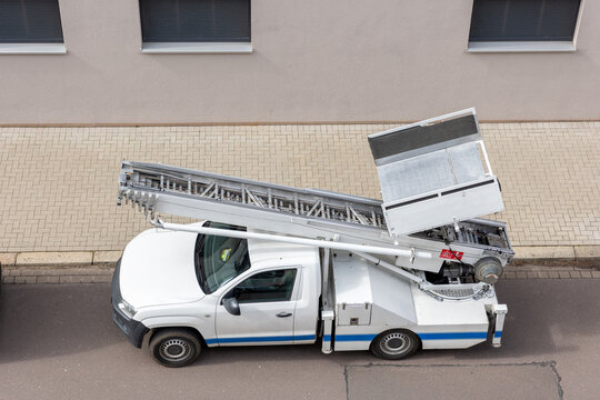 Mover service lifting ladder cargo crane platform vehicle van parked at city street. Retractable furniture elevator machine car pickup truck rental company for relocation and house moving delivery