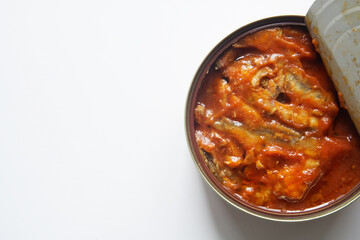 Open tin can with fish in tomato sauce. View from above. White background. Photo. Copy space