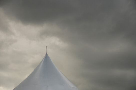 Top half of carnival big top tent with dark grey skies and cloud background
