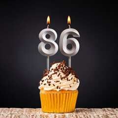 Birthday candle number 86 - Anniversary cupcake on black background