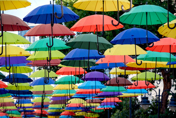 Fototapeta na wymiar many colorful umbrellas fly and hover on the city street