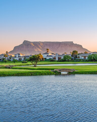 Golf course houses on the lake and the table muntain in the background during sunset, Cape Town, South Africa