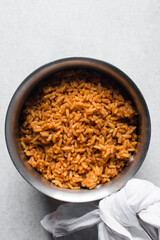Jollof rice and fried chicken in a silver saucepan, homemade nigerian jollof rice in a pot, overhead view of authentic homemade west african jollof rice