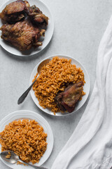 Jollof rice and fried chicken on a white plate, homemade nigerian jollof rice on a plate, overhead view of authentic homemade west african jollof rice