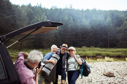 Group of senior friends taking a picture with a smartphone while hiking in the forest and mountains
