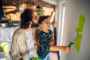 Young father and son renovating and painting walls at home