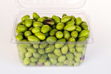 Freshly harvested green natural olives in plastic box on white surface