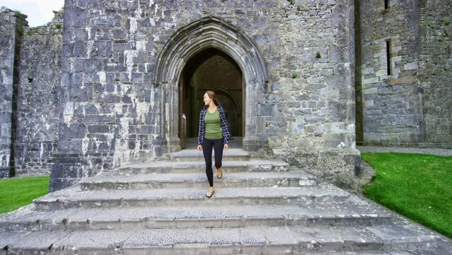 Girl exits historical cathedral ruins Rock of Cashel.
