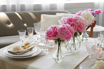 Stylish table setting with beautiful peonies and burning candles indoors