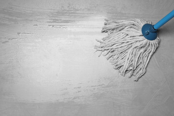 Cleaning grey floor with mop, top view. Space for text