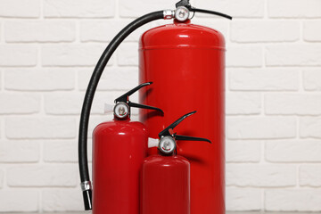 Obraz premium Red fire extinguishers near white brick wall