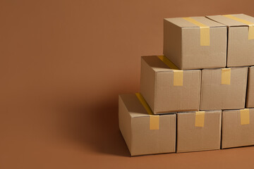 Stack of many cardboard boxes on brown background, space for text