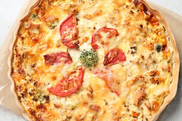 Tasty quiche with cheese and tomatoes on light grey table, top view