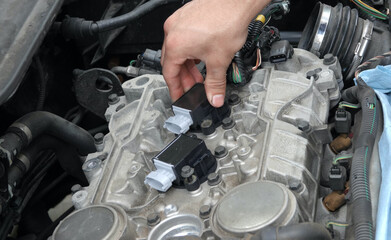 Hand pushing new ignition coil into place  