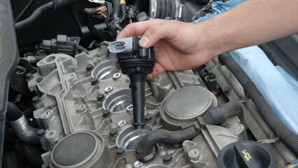 Close up of hand inserting new ignition coil into engine 
