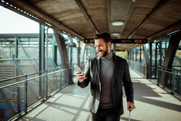 Young man using a smartphone while waiting for his train in a train station