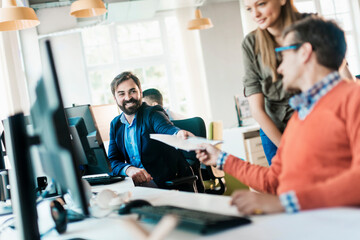 Young and diverse group of coworkers going over paperwork in a startup company office