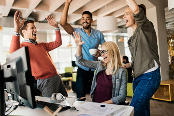Young group of diverse coworkers celebrating in the office of a startup company