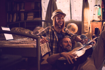 Young couple playing the guitar in the bedroom at home