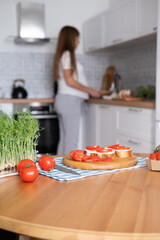 Pregnant young woman preparing healthy sandwiches with microgreens and vegetables at home in the kitchen