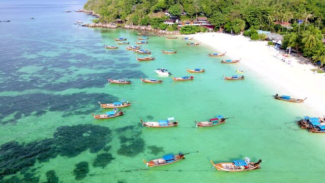 Koh Lipe Island Southern Thailand with turqouse colored ocean and white sandy beach, longtail boats in the ocean from above with a drone