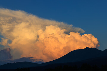 夕日を浴びオレンジ色に染まる山の上の雲