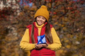 positive teen kid with present box in autumn