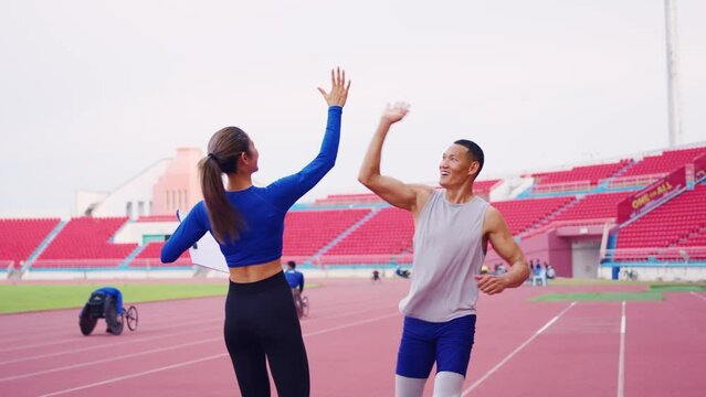 Asian athlete with prosthetic blades and trainer workout in stadium. 