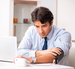 Man under stress measuring his blood pressure