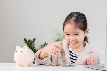Fototapeta na wymiar Asian little cute girl wearing a cream suit analyzing coins finance and investment