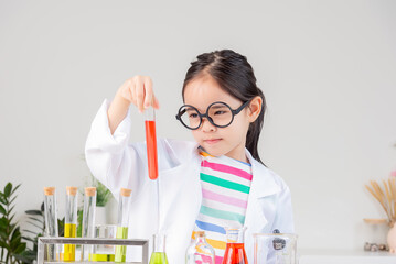 Asian little girl working with test tube science experiment in white classroom