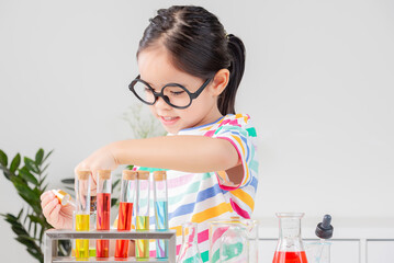 Asian little girl working with test tube science experiment in white classroom