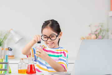 Asian little girl working with test tube science experiment in white classroom