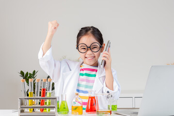 Asian little girl working with test tube science experiment in white classroom