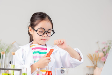 Asian little girl working with test tube science experiment in white classroom