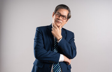 Portrait of an elderly Asian businessman, posing on a blue background