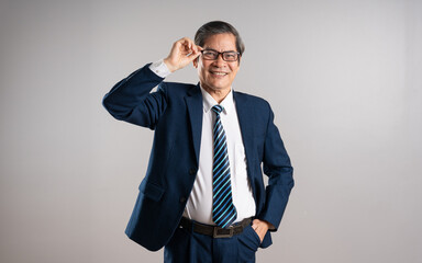 Portrait of an elderly Asian businessman, posing on a blue background