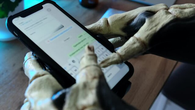 Skeleton bone fingers typing messages on the screen of a smartphone. Happy Halloween, technology and social media have become integral parts of modern-day celebrations. 