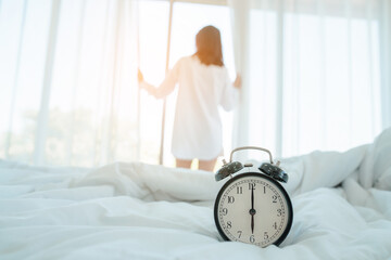 Young woman at home in morning, focus on alarm clock, alarm clock wake up woman in the room